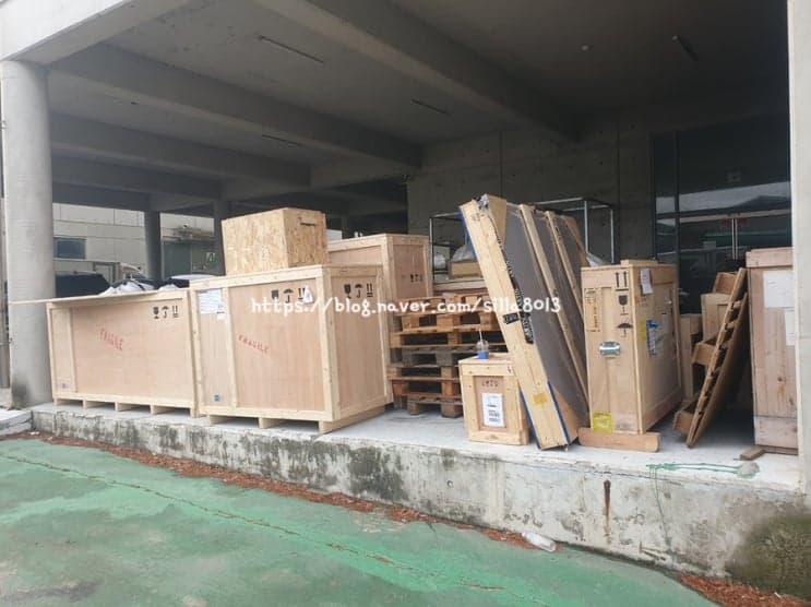 기둥 아래 목재 크레이트와 팔레트를 정리하는 모습